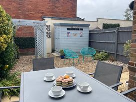 A garden with a table and chairs, shed and cupcakes at Plain Sailing in Weymouth