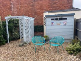 A garden with a trellis, chairs, and a shed at Plain Sailing in Weymouth