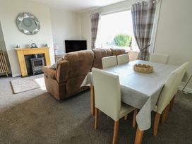 A living room with a sofa and dining table at Pentre Iago Rhoscolyn