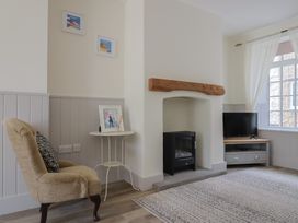 A living room with an armchair and fireplace at Belfry Cottage in Colyton