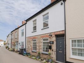 Exterior view of a cottage with stone wall and front door at Belfry Cottage in Colyton