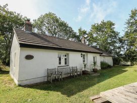 A house with a bench and potted plants in an outdoor space at Llainorfa in Maenygroes near New Quay