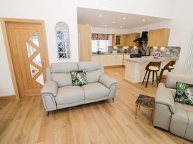 A living room with a sofa and kitchen area at The Barn in Astwood Bank