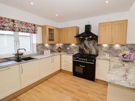 A kitchen with a black stove and wooden cabinets at The Barn in Astwood Bank