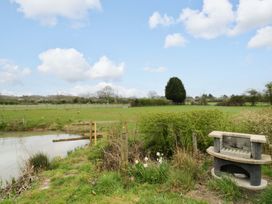 An outdoor area with a pond and a bench at The Barn in Astwood Bank