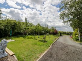 A garden with a pathway lined by trees and statues at The Barn Astwood Bank