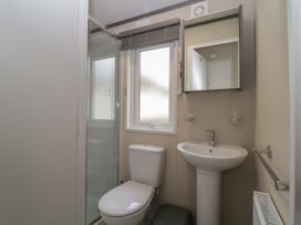 A bathroom with a toilet sink shower cubicle window and wall mirror at Caravan 7 in Plymouth