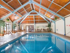 An indoor swimming pool with chairs and tables along the sides at Caravan 7 in Plymouth