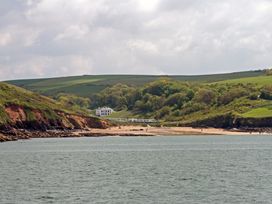 A beach with cliffs green hills and a white house near the shoreline at Caravan 7 in Plymouth