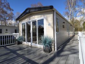 A mobile home with sliding glass doors and plants on a deck at The Meadows 45 in Tattershall