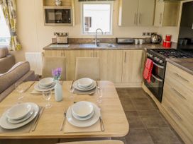 A kitchen and dining area with set table and appliances at The Meadows 45 in Tattershall