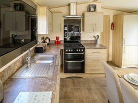 A kitchen with a sink stove oven cabinets and dining table at The Meadows 45 Tattershall