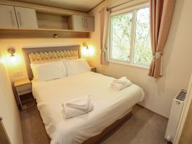 A bedroom with a double bed white bedding folded towels bedside tables and a window with curtains at The Meadows 45 in Tattershall
