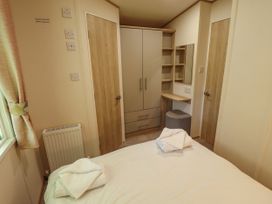 A bedroom with a bed towels on it a wardrobe dressing table with a stool and two doors at The Meadows 45 in Tattershall