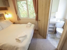 A bedroom with a bed and towels and an open door to a bathroom at The Meadows 45 in Tattershall