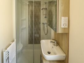 A bathroom with a shower cabin a sink and a towel on a radiator at The Meadows 45 in Tattershall
