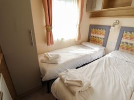 A bedroom with two single beds with white bedding and towels near a window at The Meadows 45 in Tattershall
