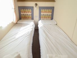A bedroom with two single beds with patterned headboards and white bedding at The Meadows 45 in Tattershall