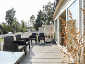 A patio with black chairs and a glass table outside a mobile home at The Meadows 45 in Tattershall