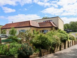 A building with a tiled roof surrounded by plants and a wooden fence at 18 Manleigh Park in Combe Martin