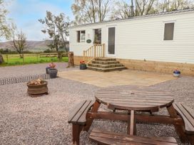 An outdoor area with a wooden picnic table fire pit gravel and steps leading to a mobile home at Grandads Shack in Trevethin near Pontynewynydd