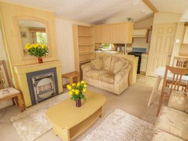 A living room with a sofa a coffee table with yellow flowers and a fireplace at Grandads Shack in Trevethin near Pontynewynydd