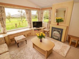 A living room with a coffee table flowers fireplace tv and large windows at Grandads Shack in Trevethin near Pontynewynydd