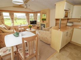 An open plan living area with dining table chairs sofa armchair television and kitchen at Grandads Shack in Trevethin near Pontynewynydd