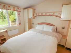 A bedroom with a double bed beside wardrobes and a window with curtains at Grandads Shack in Trevethin near Pontynewynydd
