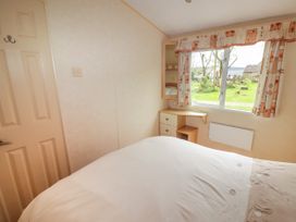 A bedroom with a bed a door a small dressing table and a window showing a garden at Grandads Shack in Trevethin near Pontynewynydd
