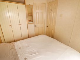 A bedroom with a bed white bedding three cream wardrobe doors wall mirror and two closed beige doors at Grandads Shack in Trevethin near Pontynewynydd