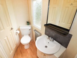A bathroom with a toilet a sink a mirror and a window at Grandads Shack in Trevethin near Pontynewynydd