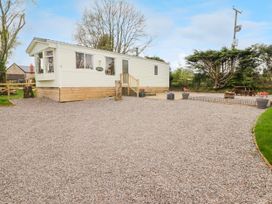 A white mobile home on a gravel area with a wooden picnic table and fire pit near trees at Grandads Shack in Trevethin near Pontynewynydd