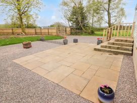 A stone patio with stairs leading to a door and several potted plants on a gravel yard at Grandads Shack in Trevethin near Pontynewynydd