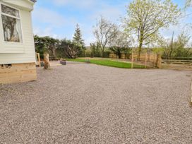 A gravel driveway leading to a wooden gate with grass and trees in the background at Grandads Shack in Trevethin near Pontynewynydd