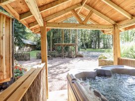 A hot tub with a view of a garden area featuring a table and chairs at Tanglewood Shepherds Hut Welshpool