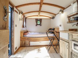 A living room with a bed and a kitchen area at Tanglewood Shepherds Hut in Welshpool