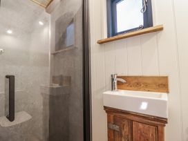 A bathroom with a shower and a sink at Tanglewood Shepherds Hut in Welshpool