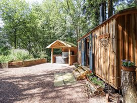 An outdoor area with a wooden cabin and hot tub at Tanglewood Shepherds Hut in Welshpool