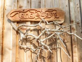 A wooden sign with the name Tanglewood and tree branches at Tanglewood Shepherds Hut in Welshpool