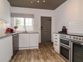 A kitchen with white cabinets, grey door, and stainless steel appliances at Cobblestone Cottage in Bude
