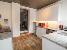 A kitchen with appliances and access to dining area at Cobblestone Cottage Bude