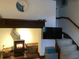 A living room with a stove, baskets, and a television at Old Town Cottage in Stratford-Upon-Avon