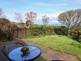 A garden with a grass lawn and flowerbed surrounded by a wooden fence with a patio table and chair at Dolphin Bach in Dolphin