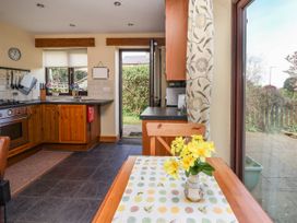A kitchen with wooden cabinets a table with a floral table runner and yellow flowers next to a glass door showing a garden at Dolphin Bach in Dolphin