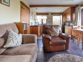 A living area with a fabric sofa and leather armchair with cushions near a kitchen and wooden dining table at Dolphin Bach in Dolphin