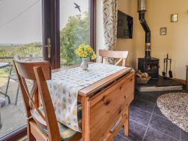 A dining area with a wooden table and chairs near a glass door next to a wood-burning stove and a TV at Dolphin Bach in Dolphin
