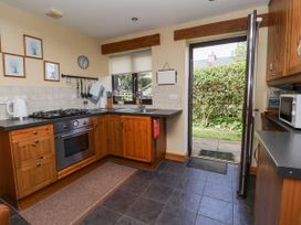 A kitchen with wooden cabinets a gas stove an oven a microwave and an open door leading to a garden at Dolphin Bach in Dolphin