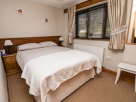 A bedroom with a double bed bedside tables window with curtains and blinds and a white bench at Dolphin Bach in Dolphin