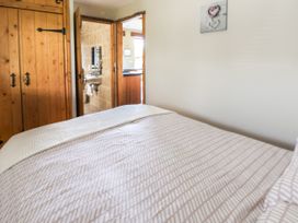 A bedroom with a bed and a wooden wardrobe with a view into a bathroom and kitchen at Dolphin Bach in Dolphin